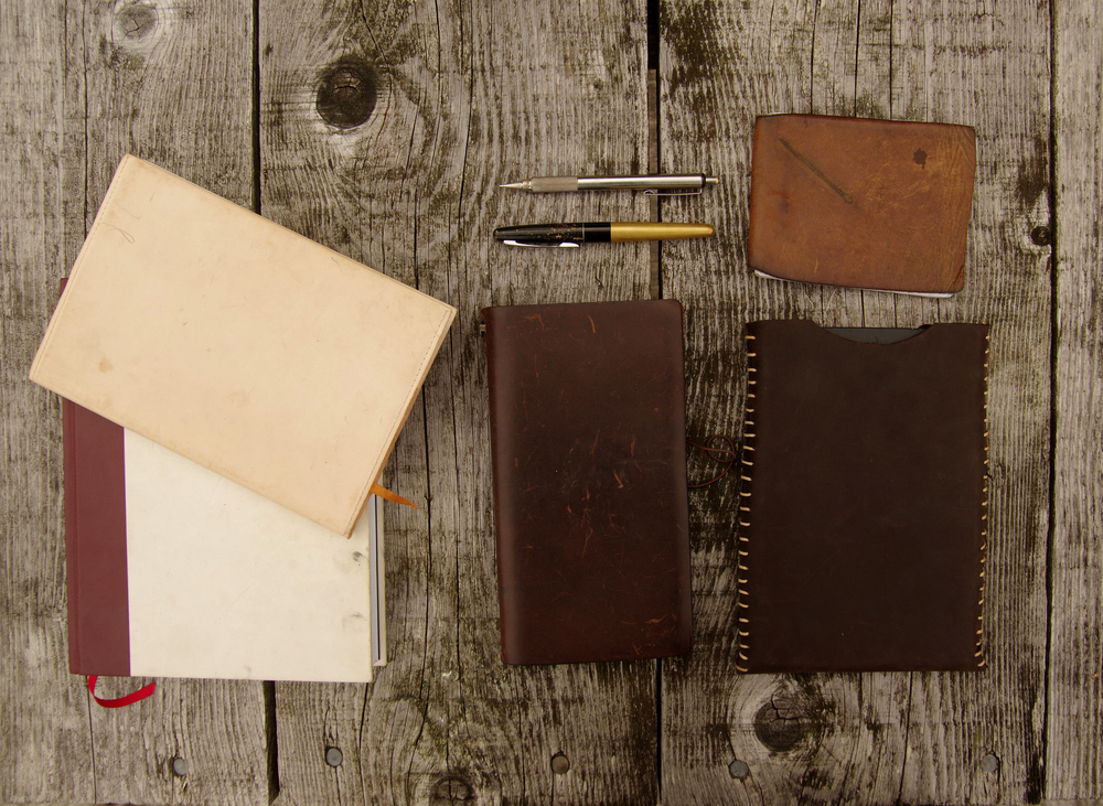 Five notebooks and pens on wood background